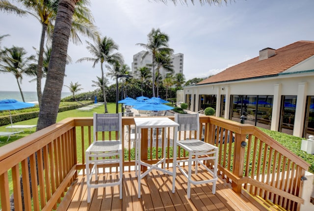 wooden deck featuring a water view and a lawn