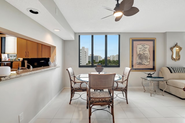 dining room with a textured ceiling, light tile patterned floors, and ceiling fan