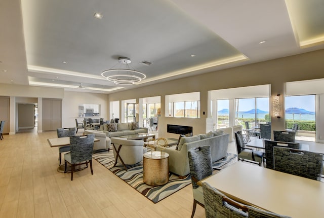 living room featuring plenty of natural light, light wood-type flooring, and a tray ceiling