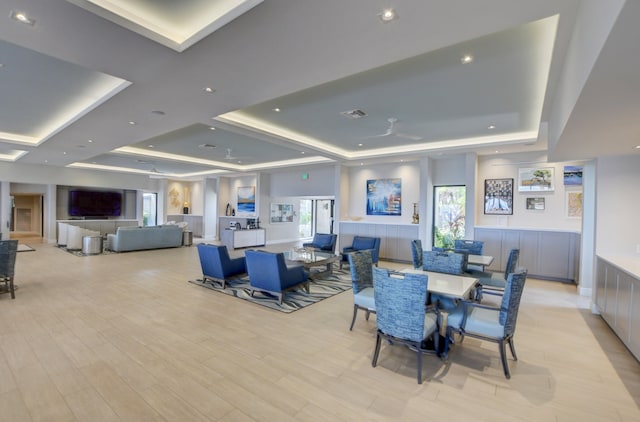 dining space featuring light wood-type flooring, a tray ceiling, and plenty of natural light