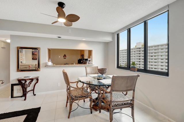 dining space featuring ceiling fan, light tile patterned floors, and a textured ceiling