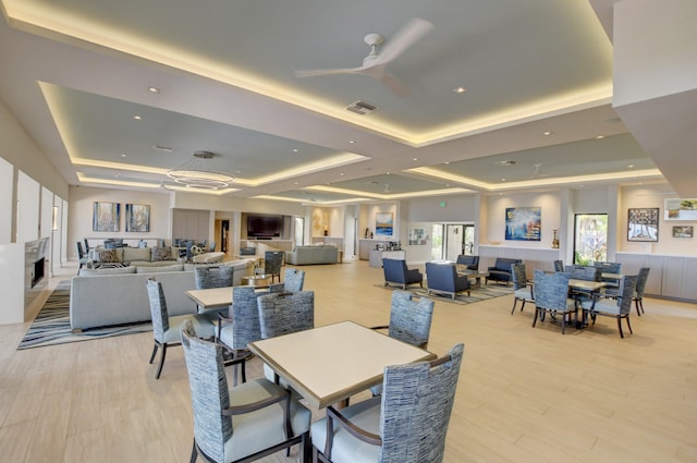 dining area featuring a tray ceiling, light hardwood / wood-style floors, and ceiling fan