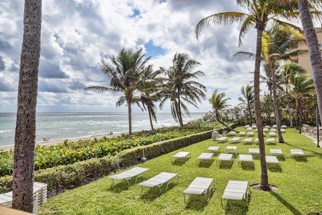 view of community with a beach view, a water view, and a lawn