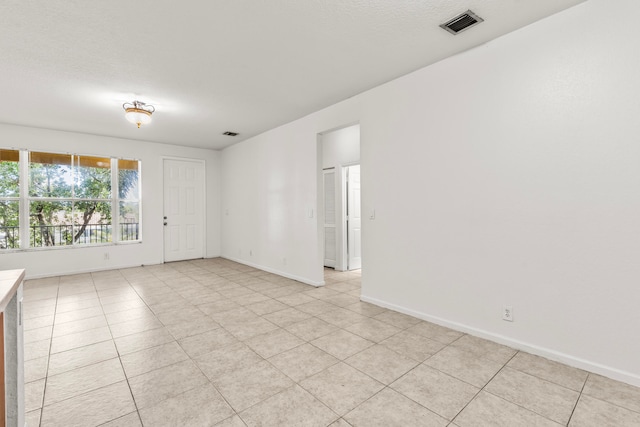 unfurnished room featuring a textured ceiling and light tile patterned flooring