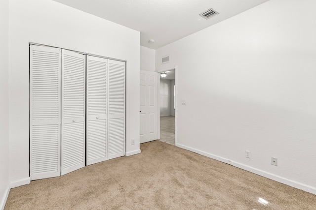 unfurnished bedroom with a closet and light carpet