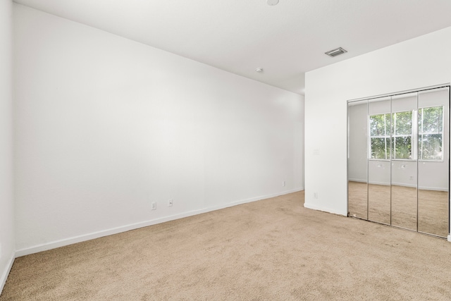 unfurnished bedroom with a closet and light colored carpet