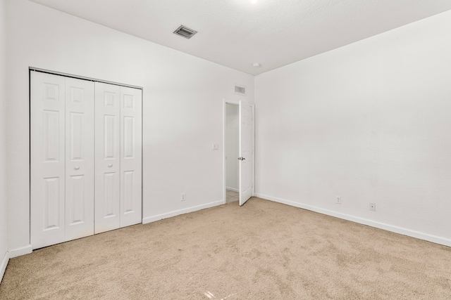 unfurnished bedroom featuring a closet and light carpet