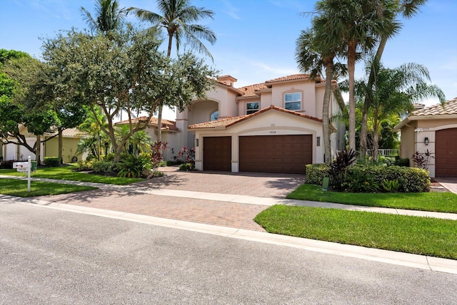 mediterranean / spanish house with stucco siding, a tiled roof, and decorative driveway