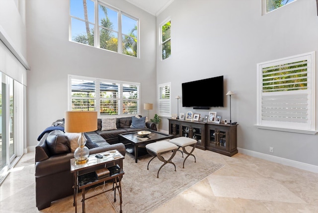 living room with crown molding, baseboards, and a towering ceiling