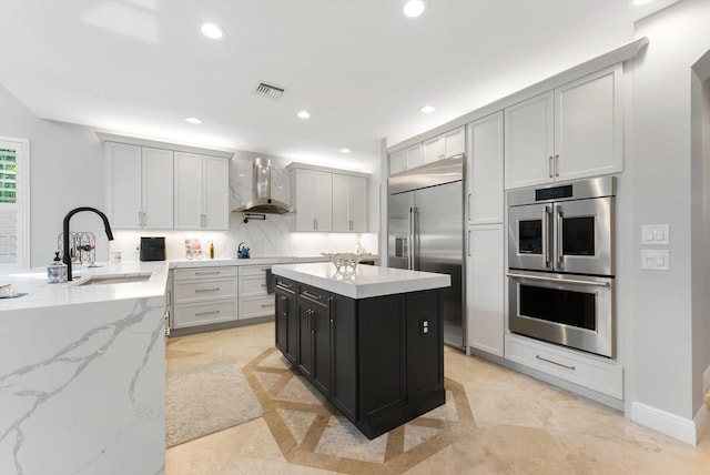 kitchen with visible vents, wall chimney range hood, recessed lighting, appliances with stainless steel finishes, and a sink