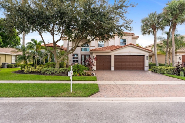 view of front facade with stucco siding, a tile roof, decorative driveway, a front yard, and an attached garage