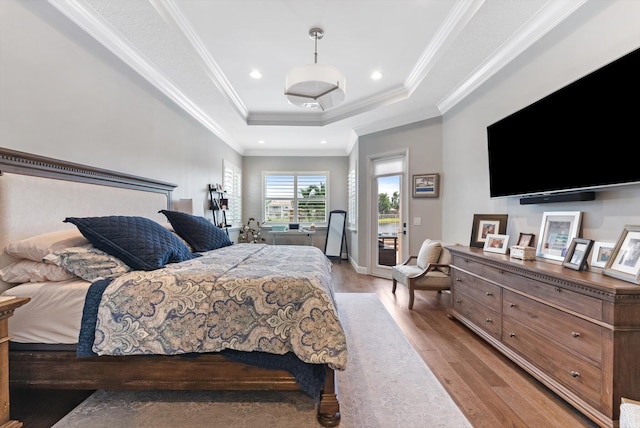 bedroom featuring a tray ceiling, recessed lighting, ornamental molding, light wood-style floors, and access to outside