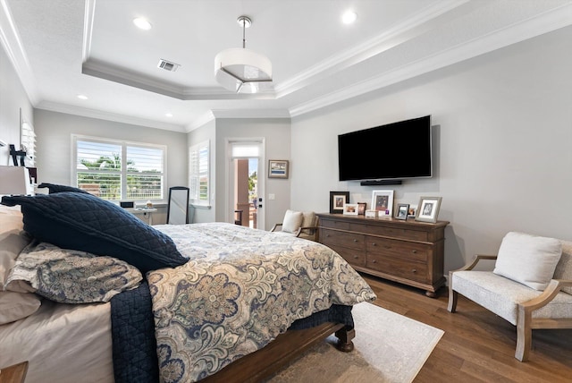 bedroom featuring visible vents, a tray ceiling, ornamental molding, recessed lighting, and wood finished floors