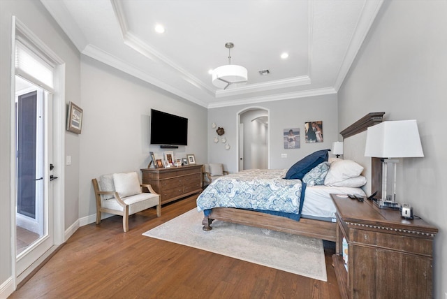 bedroom with wood finished floors, visible vents, arched walkways, crown molding, and a raised ceiling