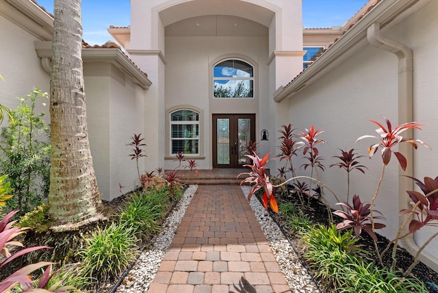 doorway to property with a tile roof, french doors, and stucco siding