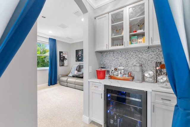 bar featuring beverage cooler, ornamental molding, decorative backsplash, a dry bar, and light colored carpet