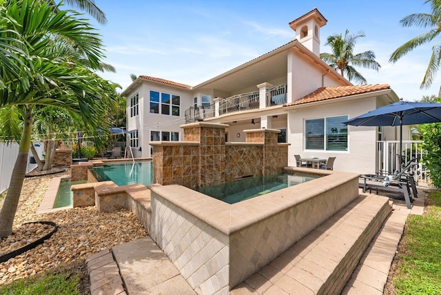 exterior space with a fenced in pool, fence, a tiled roof, stucco siding, and a balcony