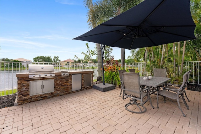 view of patio with area for grilling, an outdoor kitchen, outdoor dining area, and fence