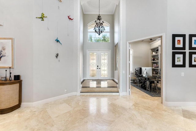 entryway with french doors, baseboards, a high ceiling, and an inviting chandelier