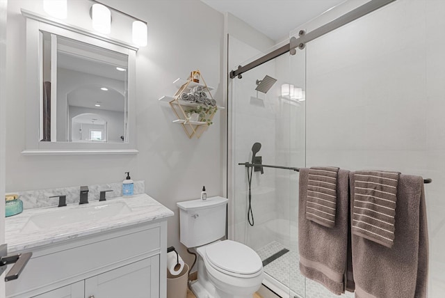 bathroom featuring a shower stall, toilet, and vanity