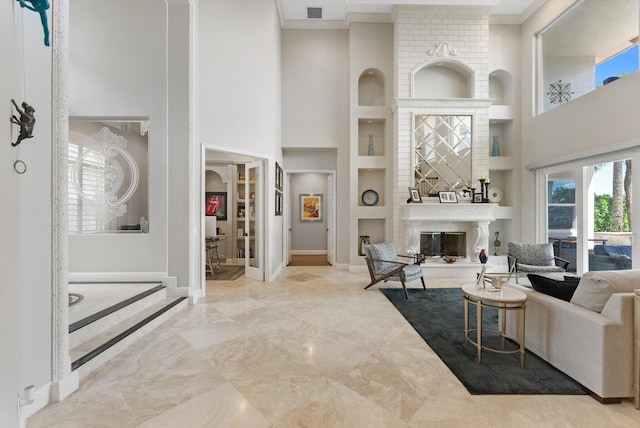 living area with a large fireplace, built in shelves, baseboards, and a towering ceiling