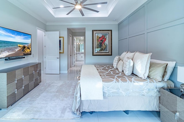 bedroom with a decorative wall, ensuite bath, a tray ceiling, and ornamental molding