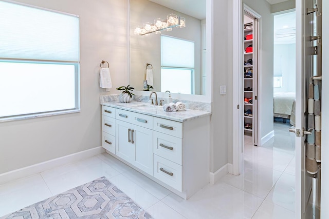 bathroom featuring vanity, tile patterned floors, a spacious closet, and baseboards