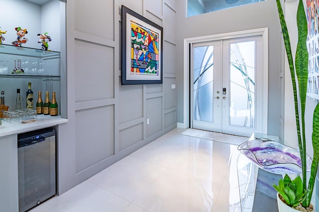 entryway with french doors, light tile patterned flooring, beverage cooler, and bar