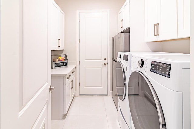 laundry area with light tile patterned flooring, cabinet space, and separate washer and dryer