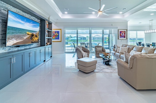 living room featuring a tray ceiling, visible vents, and ornamental molding