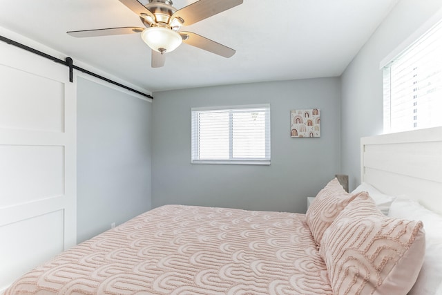 bedroom with a barn door and ceiling fan