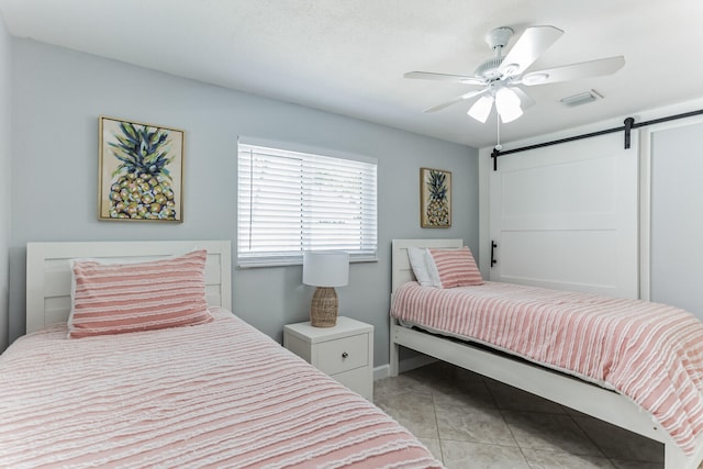 tiled bedroom featuring a barn door and ceiling fan