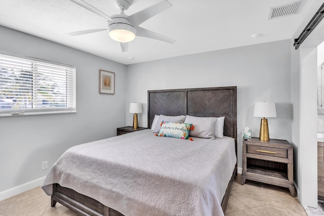 tiled bedroom featuring ceiling fan and a barn door