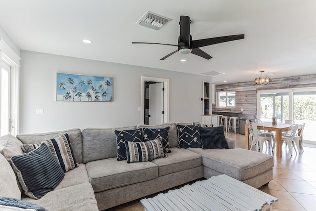 tiled living room featuring ceiling fan with notable chandelier