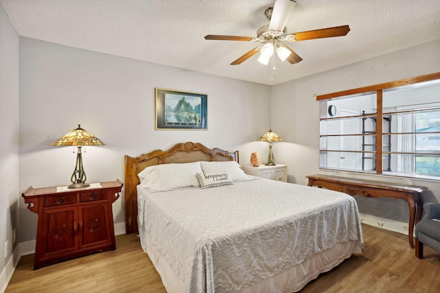 bedroom with ceiling fan, a textured ceiling, and light hardwood / wood-style flooring