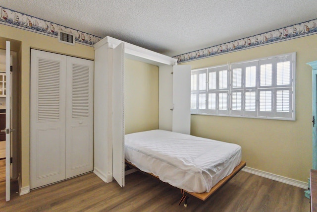 bedroom with dark wood-type flooring, a textured ceiling, and a closet