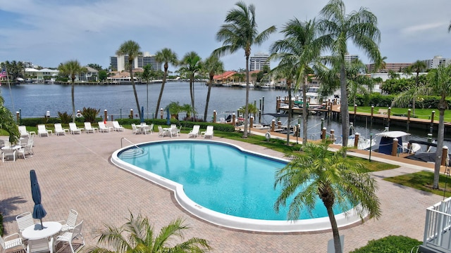 view of pool with a water view, a patio, and a dock