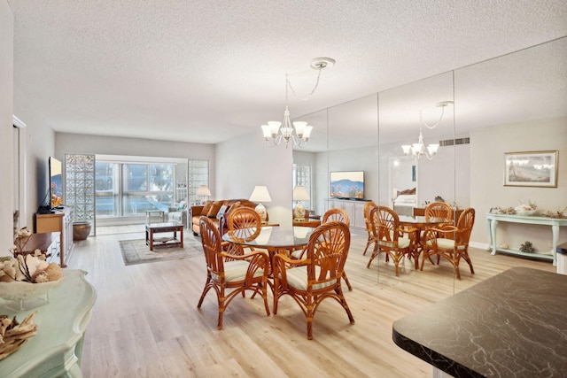 dining area featuring a textured ceiling, an inviting chandelier, and light hardwood / wood-style floors