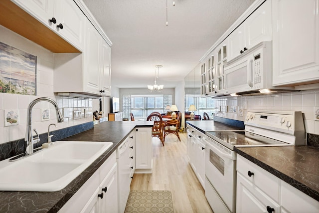 kitchen with white appliances, light hardwood / wood-style floors, sink, decorative backsplash, and a chandelier