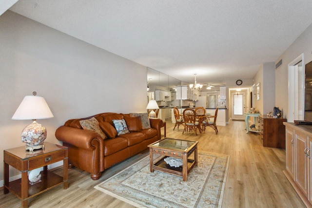 living room featuring an inviting chandelier, a textured ceiling, and light hardwood / wood-style flooring