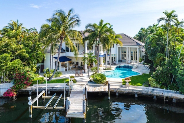 rear view of property with a patio, a water view, a balcony, and an outdoor pool