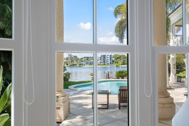 doorway to outside with a towering ceiling, light tile patterned floors, and a water view