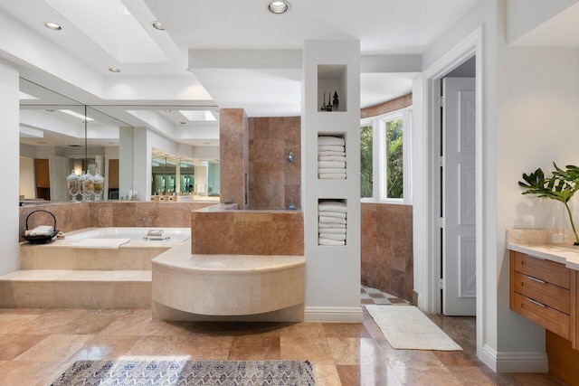 bathroom with a walk in shower, a skylight, a garden tub, and vanity