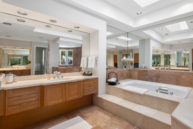 bathroom with tile patterned flooring, vanity, a tray ceiling, and a skylight