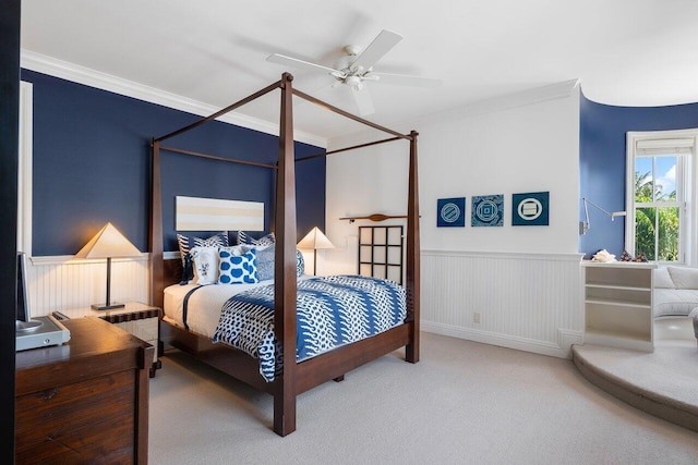 bedroom featuring wainscoting, crown molding, carpet flooring, and ceiling fan