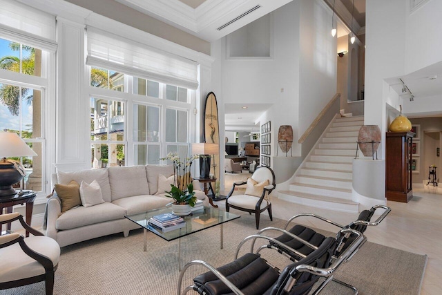 living area featuring stairway, visible vents, a towering ceiling, and wood finished floors