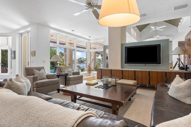 living area with ceiling fan, high vaulted ceiling, and visible vents