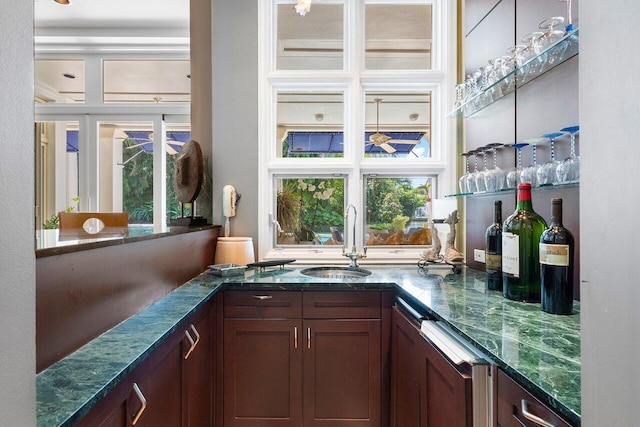 bar with dark stone countertops, sink, and dark brown cabinets