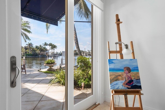 doorway to outside with a water view, a wealth of natural light, and tile patterned floors