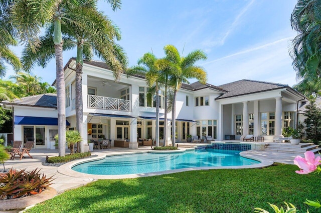 back of property featuring a yard, a patio, outdoor lounge area, a balcony, and an outdoor pool